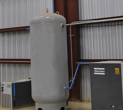 A large tank with a hose attached, likely for storage or transfer of liquids.